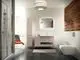 Modernes Badezimmer mit Dusche, Waschbecken und Bidet. Ideal Standard Produkte in neutralem Design, holzverkleidete Wand und viel Licht durch Fenster. Stilvolle, minimalistische Einrichtung.